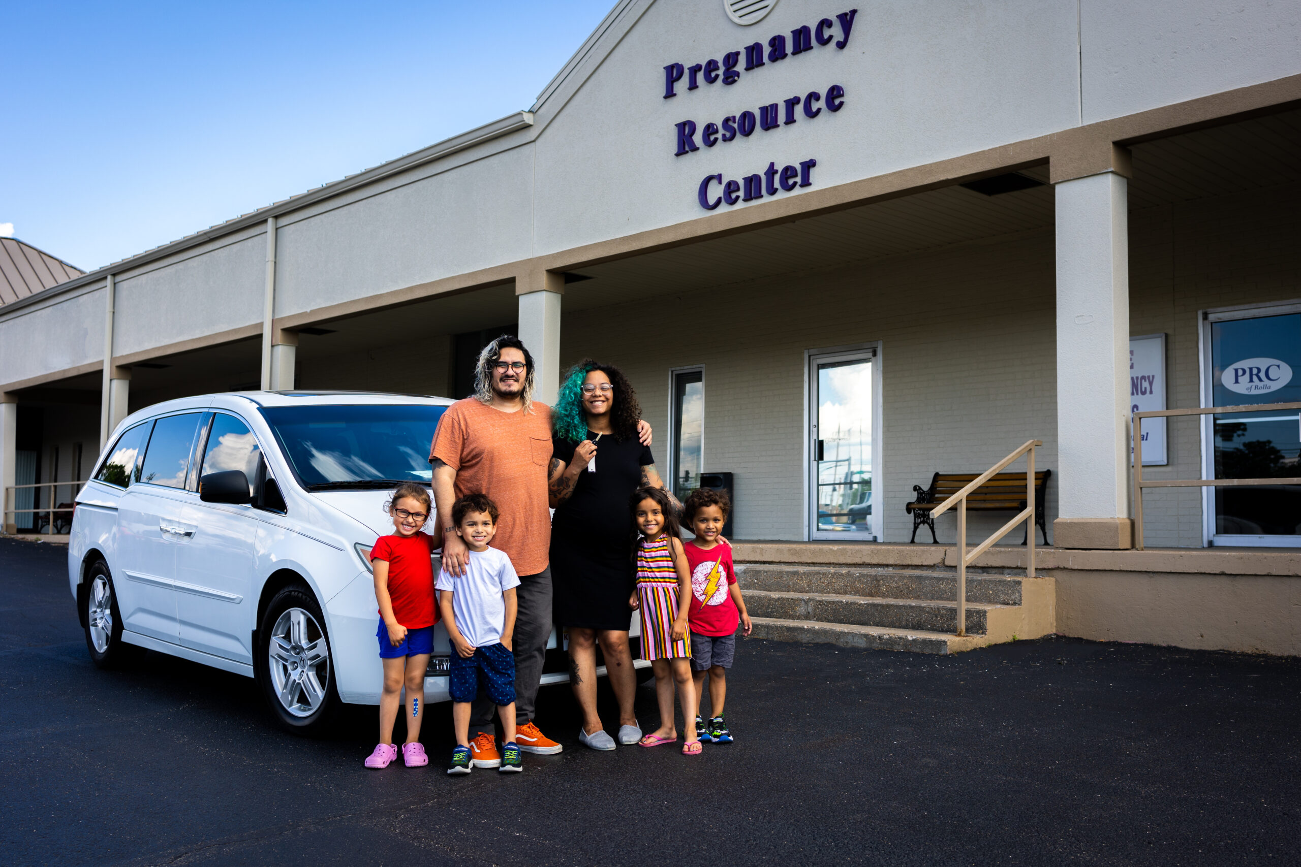 Man and woman with four children in front of a car at a pregnancy resource center