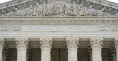 Top of Supreme Court building, white columns and a complex relief depicting justice