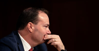 Mike Lee in a black suit looks to the right