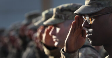Army soldiers salute in camouflage hats