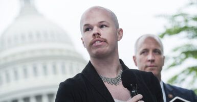 Sam Brinton man in a dress with a necklace and a mustache in front of the U.S. Capitol building