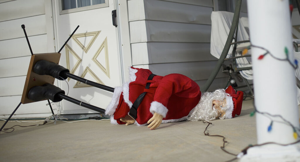 A statue of Santa Claus falls over in front of a house