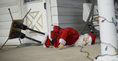 A statue of Santa Claus falls over in front of a house
