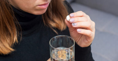 woman takes pill with glass of water