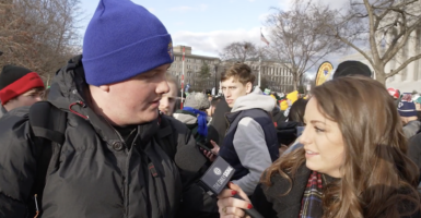 Mary Margaret Olohan in a coat interviews student wearing a coat and beanie