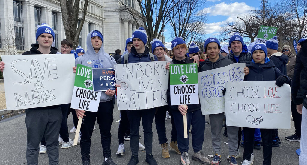 College students hold signs reading "Unborn Lives Matter" and "Choose Life"