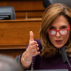 Rep. Maria Elvira Salazar wearing glasses gestures while speaking at a microphone