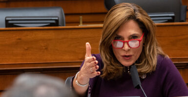 Rep. Maria Elvira Salazar wearing glasses gestures while speaking at a microphone