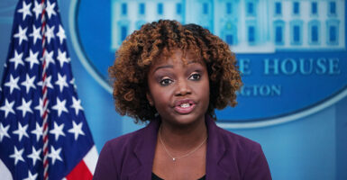 Karine Jean-Pierre in front of an American flag and the White House logo