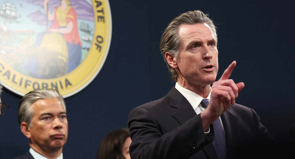 Gavin Newsom in a suit speaks in front of the California seal