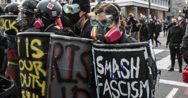 Antifa agitators march with shields and helmets in the street