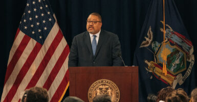 Alvin Bragg speaks in a suit in front of an American flag