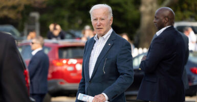 President Joe Biden wearing a suit coat and button down shirt looks strait ahead while standing outside.