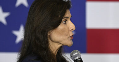Nikki Haley speaks into a microphone with an American flag behind her.