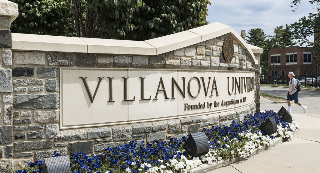 Villanova University sign with purple and white flowers below it