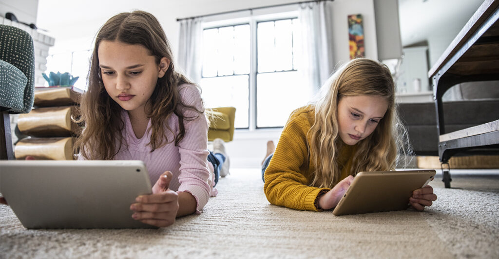 two young girls using digital tablets