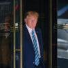 Donald Trump opens a door in a suit