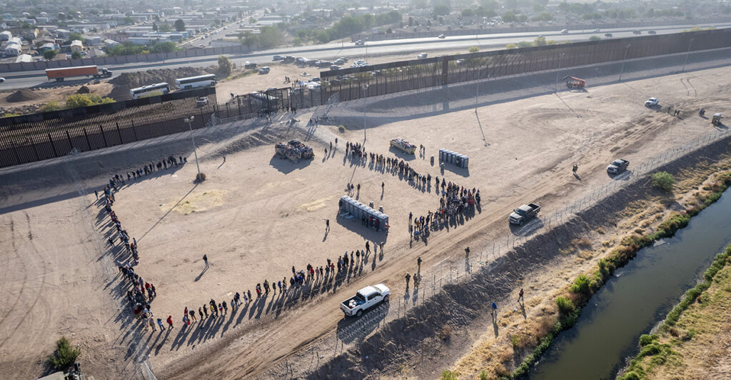 An aerial photo shows lines of illegal aliens waiting to be transported by Border Patrol at a border wall in El Paso, Texas.