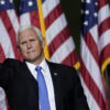 Former Vice President Mike Pence waves in front of American flags