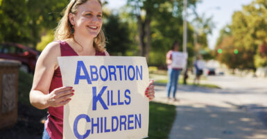A woman holds a sign reading, "Abortion Kills Children"