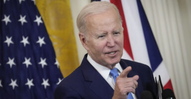 Joe Biden gestures in a suit in front of an American flag