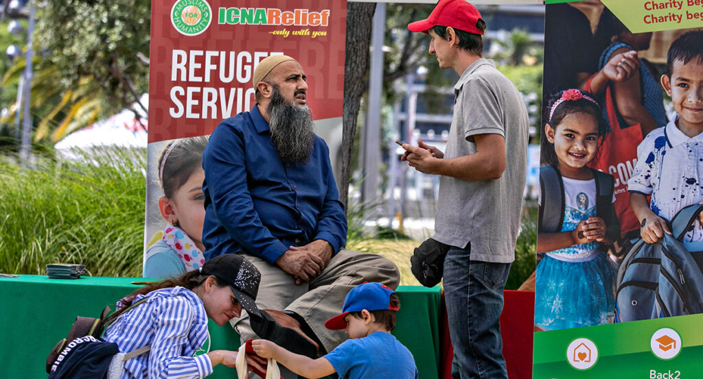 Refugee speaks in front of a Refugee Services sign