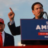 Former President Donald Trump stands behind Sen. Marco Rubio, R-Fla., as Rubio speaks to a crowd from a podium bearing a sign that reads "Save America."
