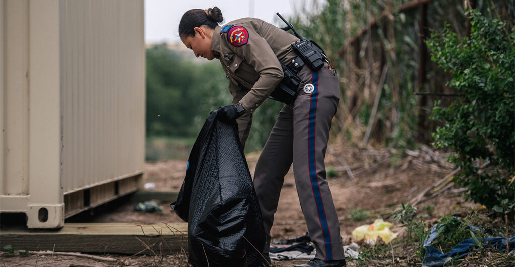 Texas Highway Patrol officer cleans up trash at a border crossing