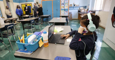 Second-grade student completes online study while sitting
