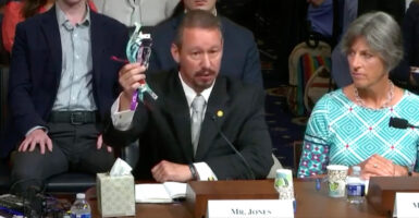 Jaeson Jones holds up a cluster of colorful wristbands during a Homeland Security Committee hearing.