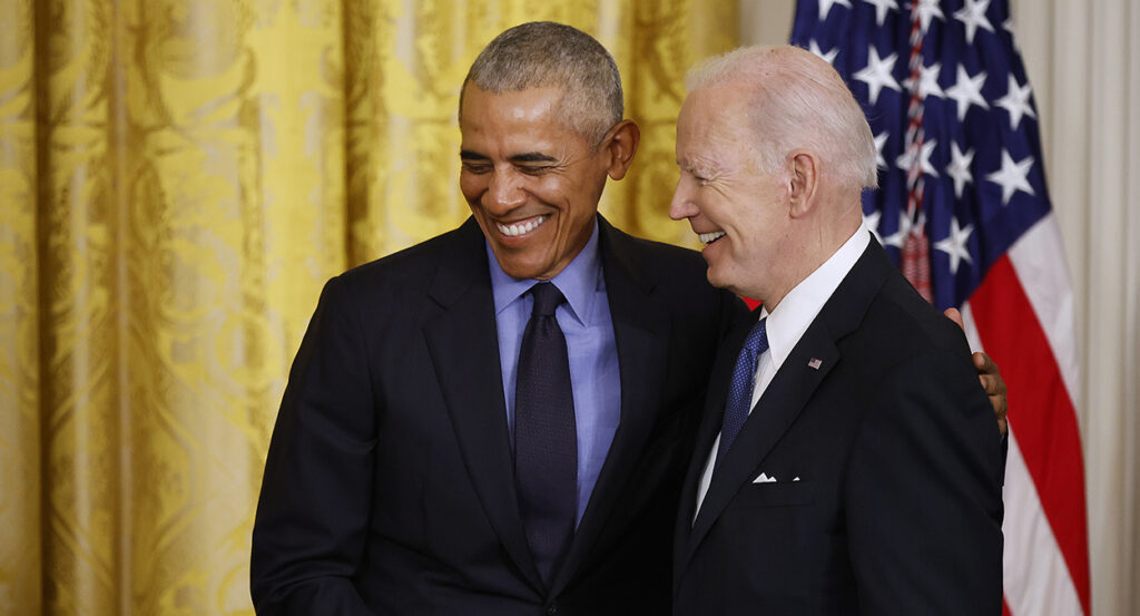 Barack Obama and Joe Biden smiling together in suits