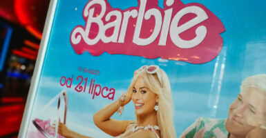 A poster for the "Barbie" movie shows Barbie and Ken driving in a pink convertible.