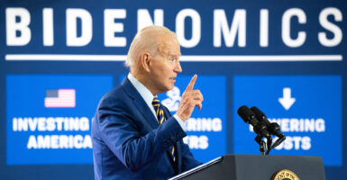 Joe Biden in a blue suit in front of a sign reading 