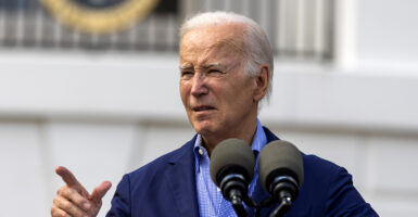 Joe Biden in a blue shirt and a blue suit jacket points to the right, looking bewildered