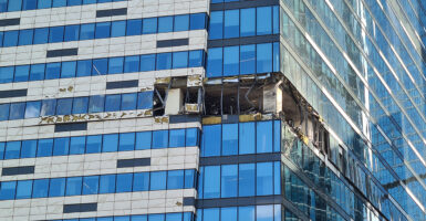 Damage is seen in the middle of a glass building skyscraper following a drone attack.