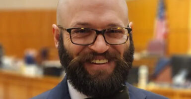 Patrick Brenner wearing glasses and a full beard in a suit