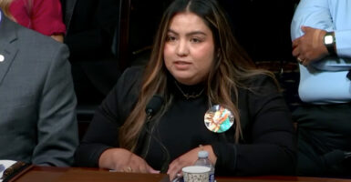 Elisa Tambunga speaks before members of Congress while seated wearing a black top.