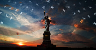 Statue of Liberty on the background of the USA flag and sunrise.