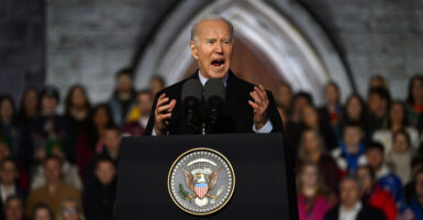 Joe Biden yells at a podium with the an American emblem on it in front of a crowd and church.