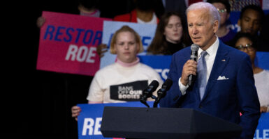 Biden speaks at a podium with pro-choice activists behind him.