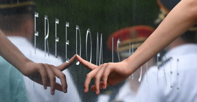 A hand touching an inscription on the Korean War Veterans Memorial that reads “Freedom is Not Free”