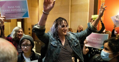 Biological male and “transgender” Minnesota State Representative Leigh Finke (c) arrives at the state Capitol to cheers from supporters