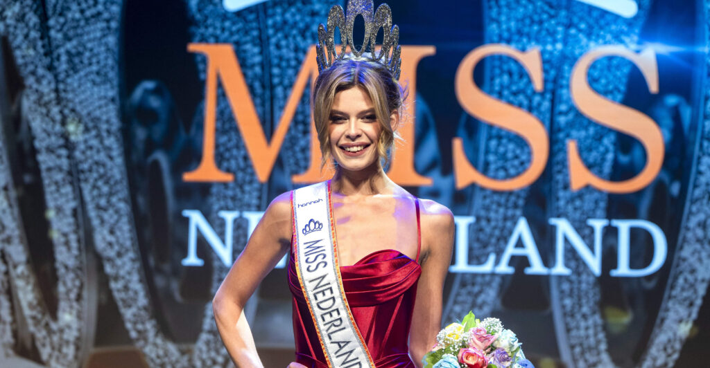 Trans model poses in a red dress, a sash that says "Miss Nederland 2023," and a crown.