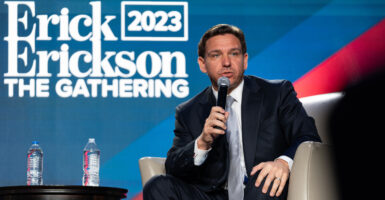 Ron DeSantis speaks in a suit with a microphone