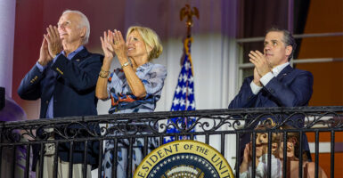 Joe Biden and Hunter Biden clap while wearing suits, with Jill Biden clapping, as well