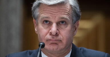 FBI Director Chris Wray looks forward in a suit