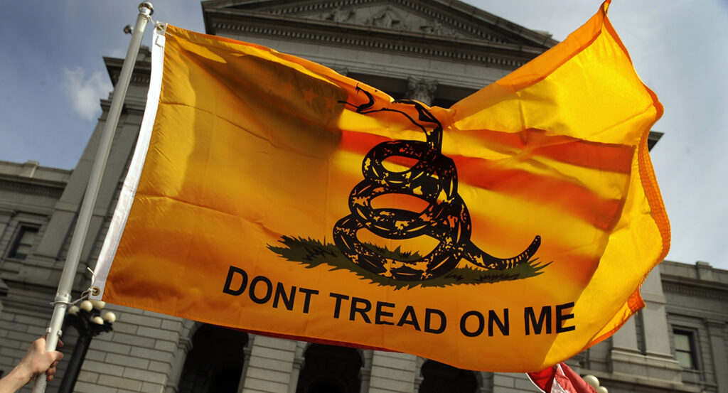 A Gadsden flag reading "Don't Tread on Me" with a rattlesnake waves in front of the Colorado State Capitol