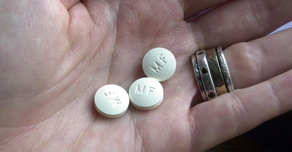 three white pills in a woman's hand