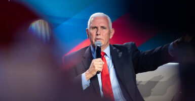 Mike Pence holds a microphone in a suit