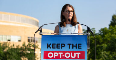 Grace Morrison stands behind a sign reading "Keep the Opt-Out"